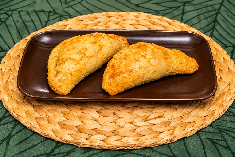 Two golden baked fish pies on a brown rectangular plate