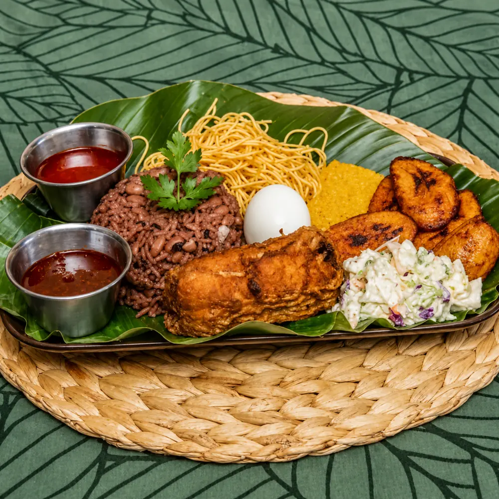 Waakye tray with rice and beans, spaghetti, boiled egg, fried fish, plantain, coleslaw and two pots of shito
